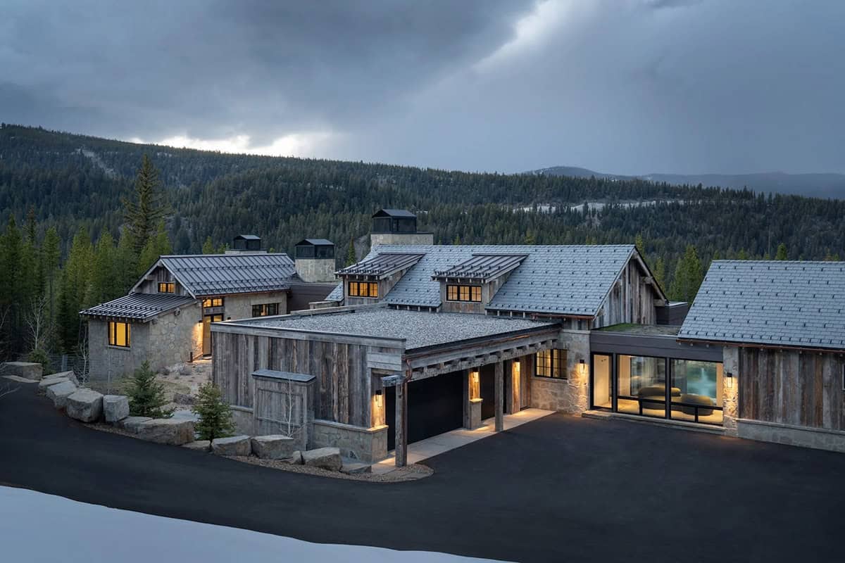 Front of the mountain home with a garage and covered walkway at dusk