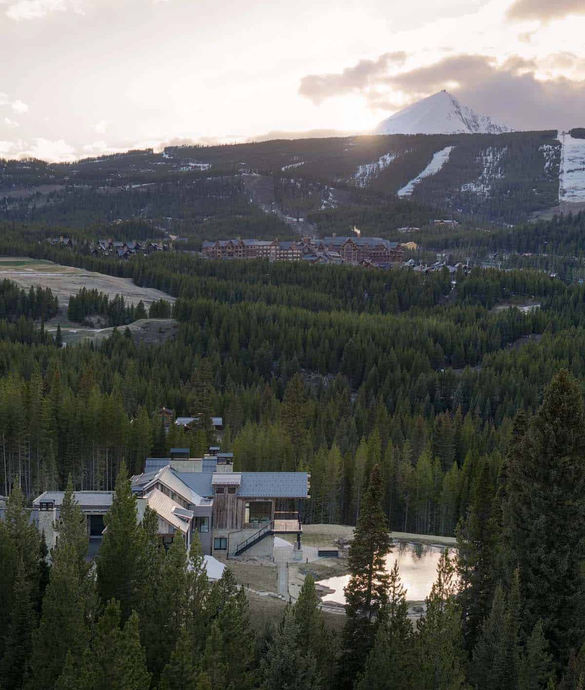 Aerial view of the home and pond with a ski mountain in the distance