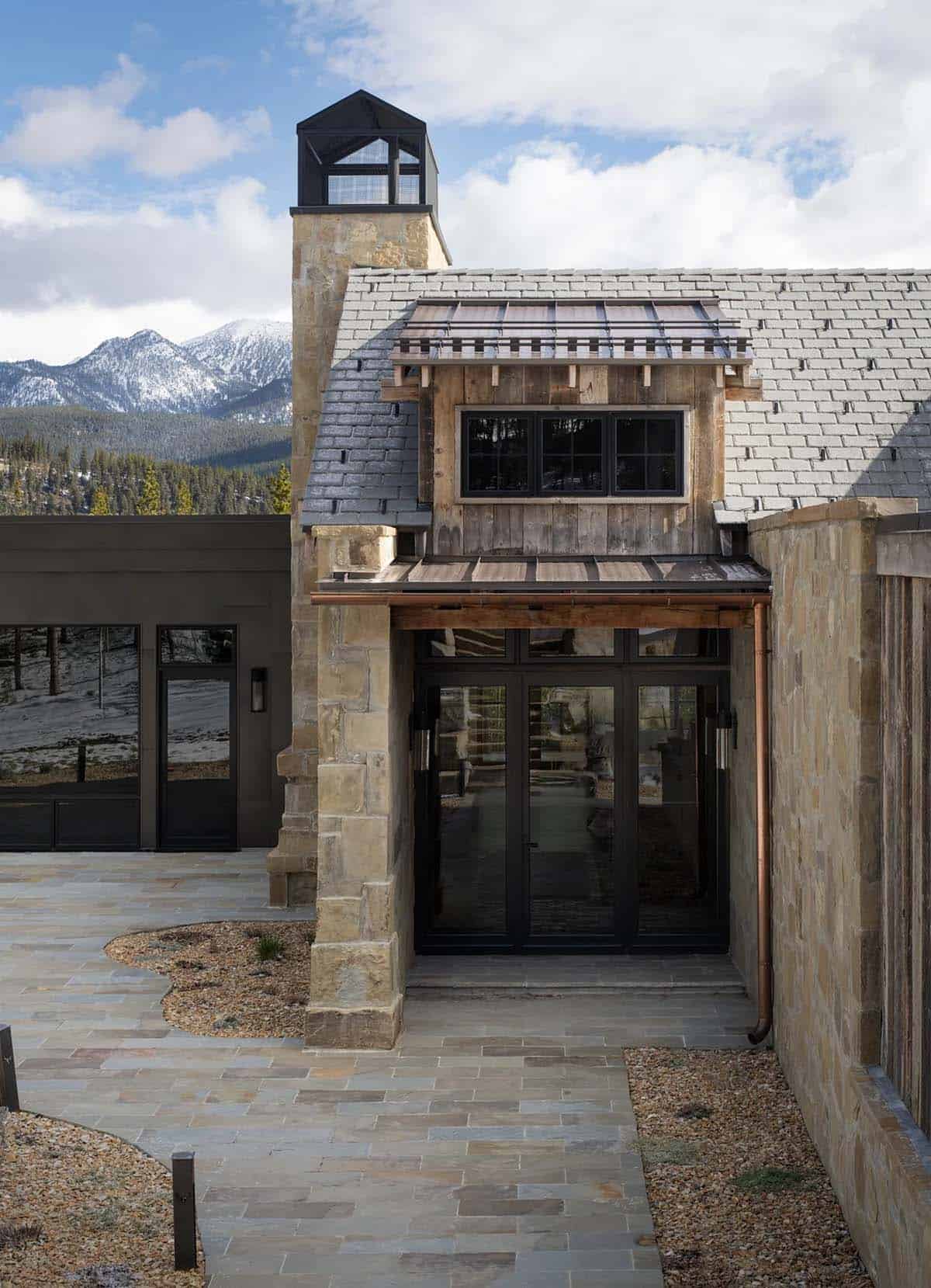 Stone entry with glass doors, a copper downspout, and mountain views