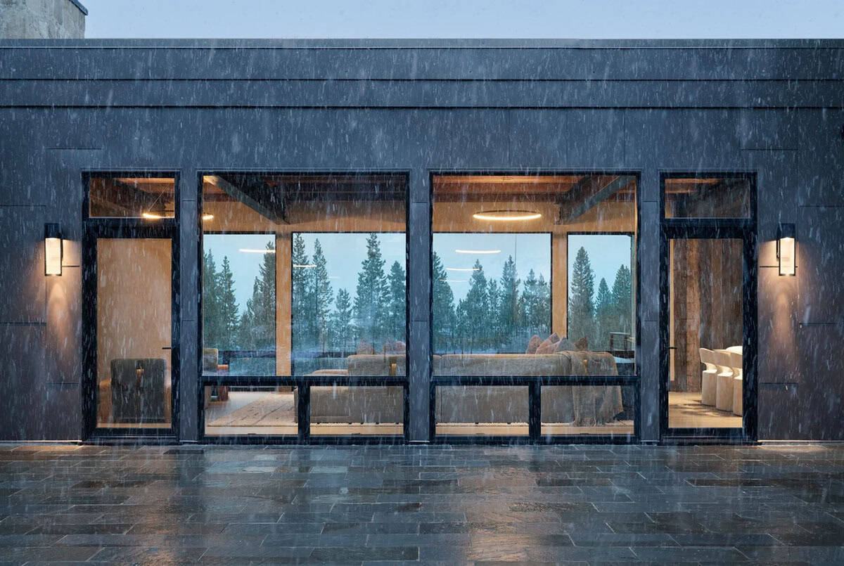 Steel-clad wall with tall windows and sconces in falling snow