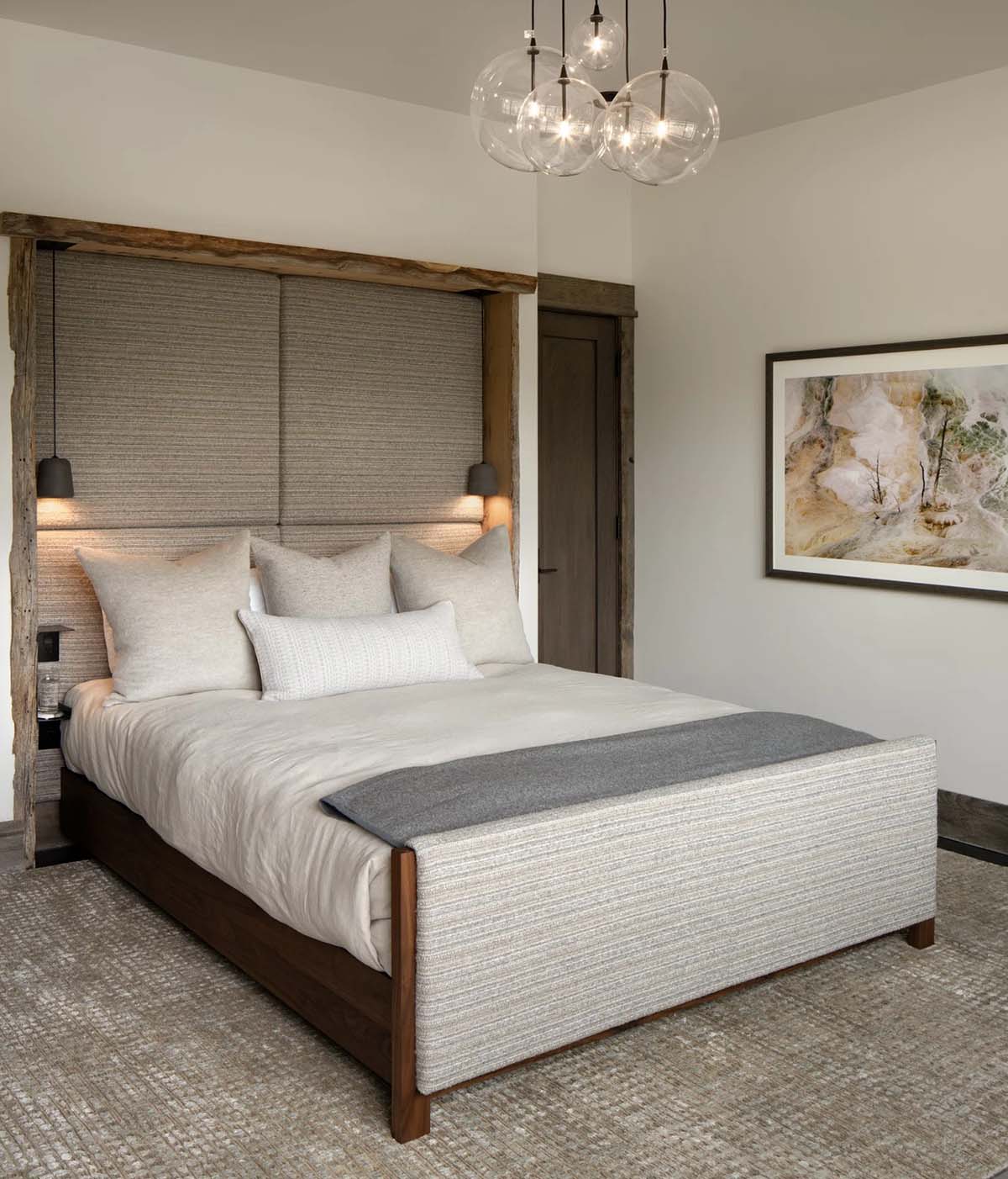 Guest bedroom with a reclaimed wood headboard wall and glass globe chandelier