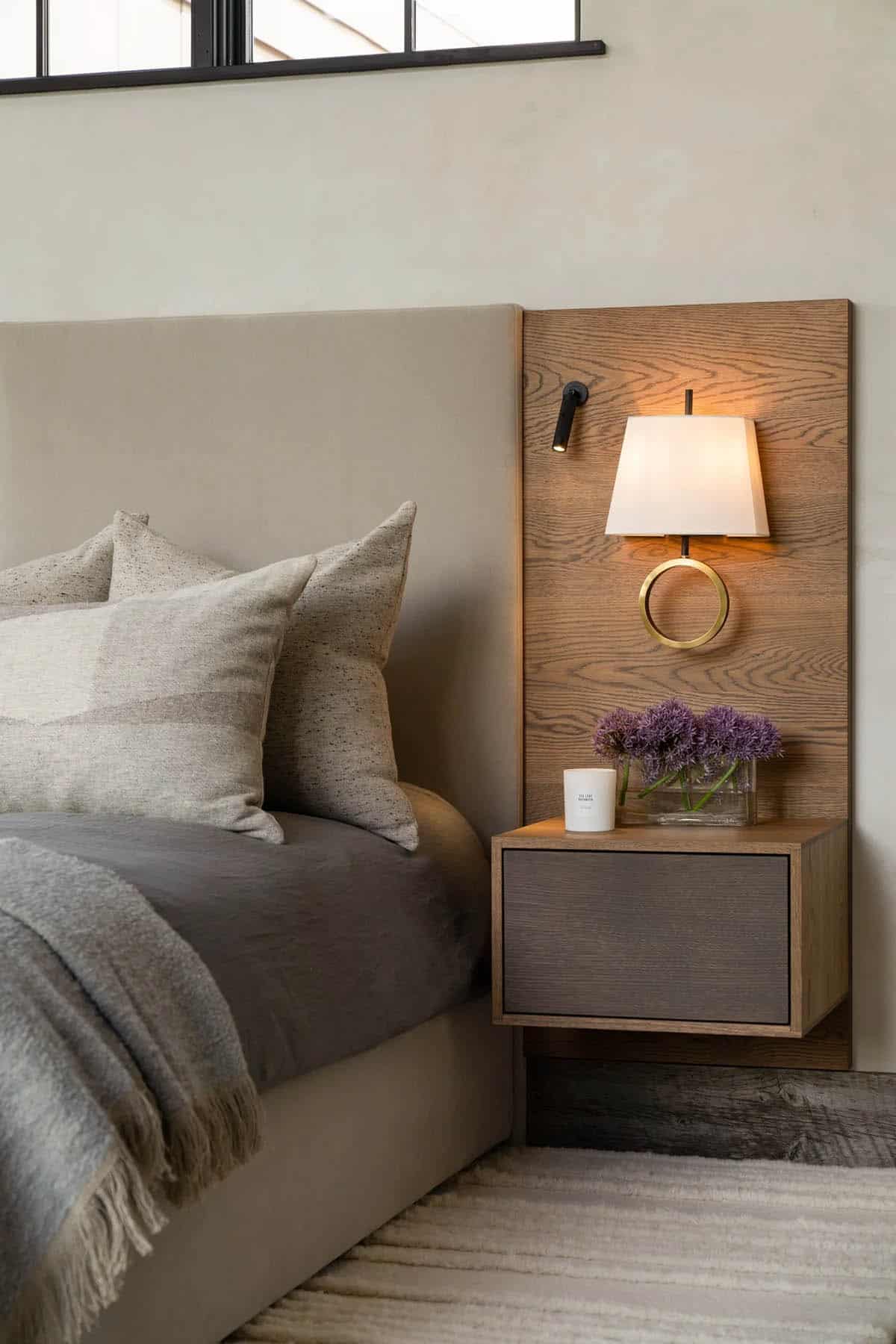 Bedside wood panel with a brass sconce above a floating nightstand