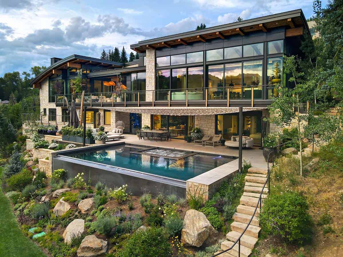 Multi-level stone and steel home with an infinity pool, boulders, and a stone staircase