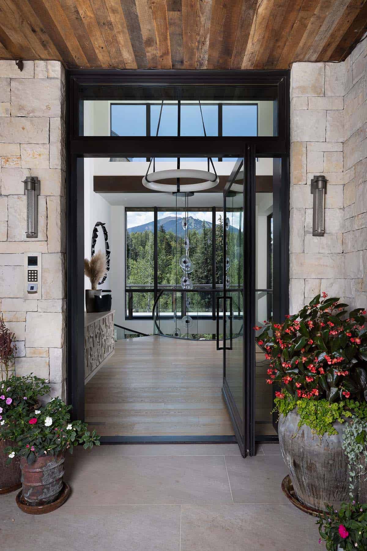 Glass pivot front door opening to a foyer with a mountain view
