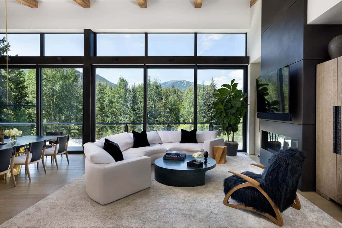 Living room with floor-to-ceiling windows, curved white sofa, and a black fireplace wall