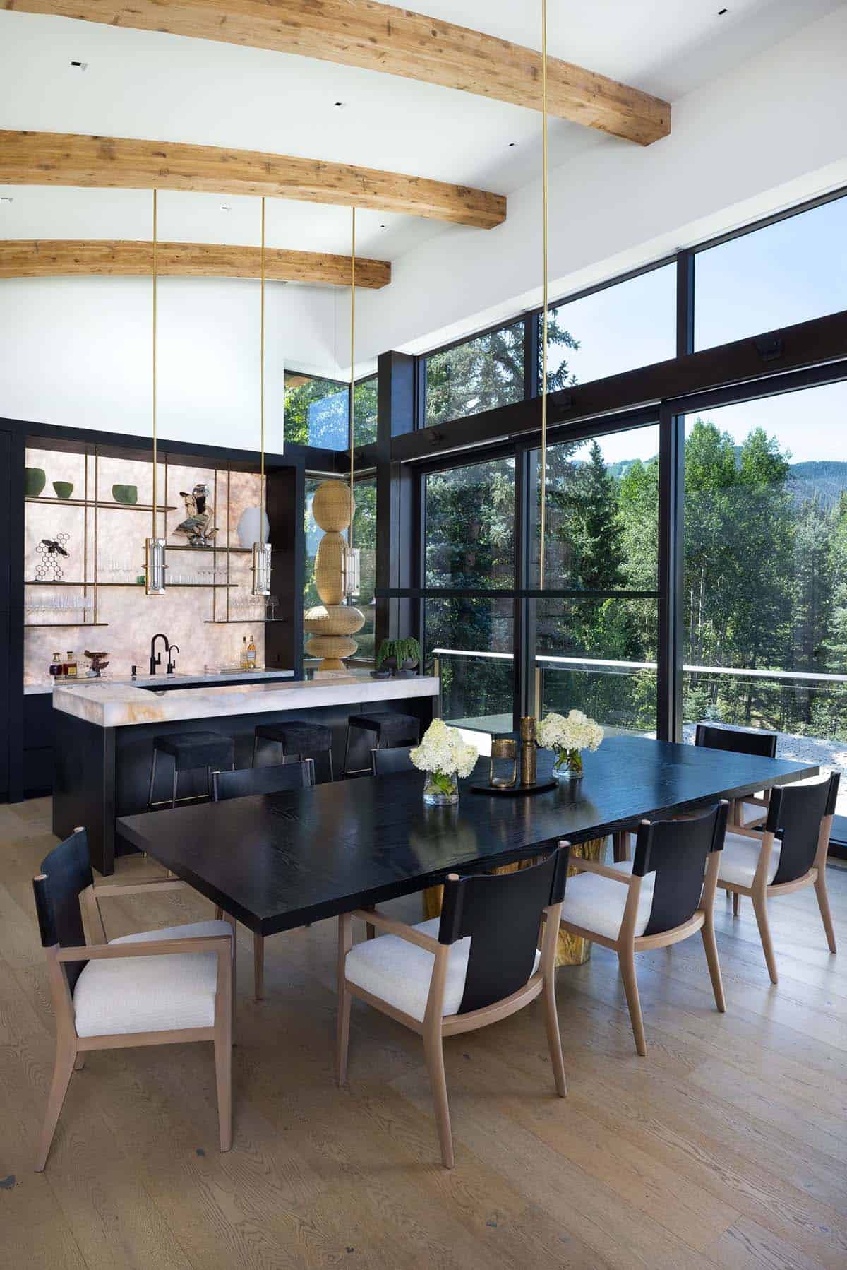 Dining room with curved wood beams, black table, and a backlit onyx bar
