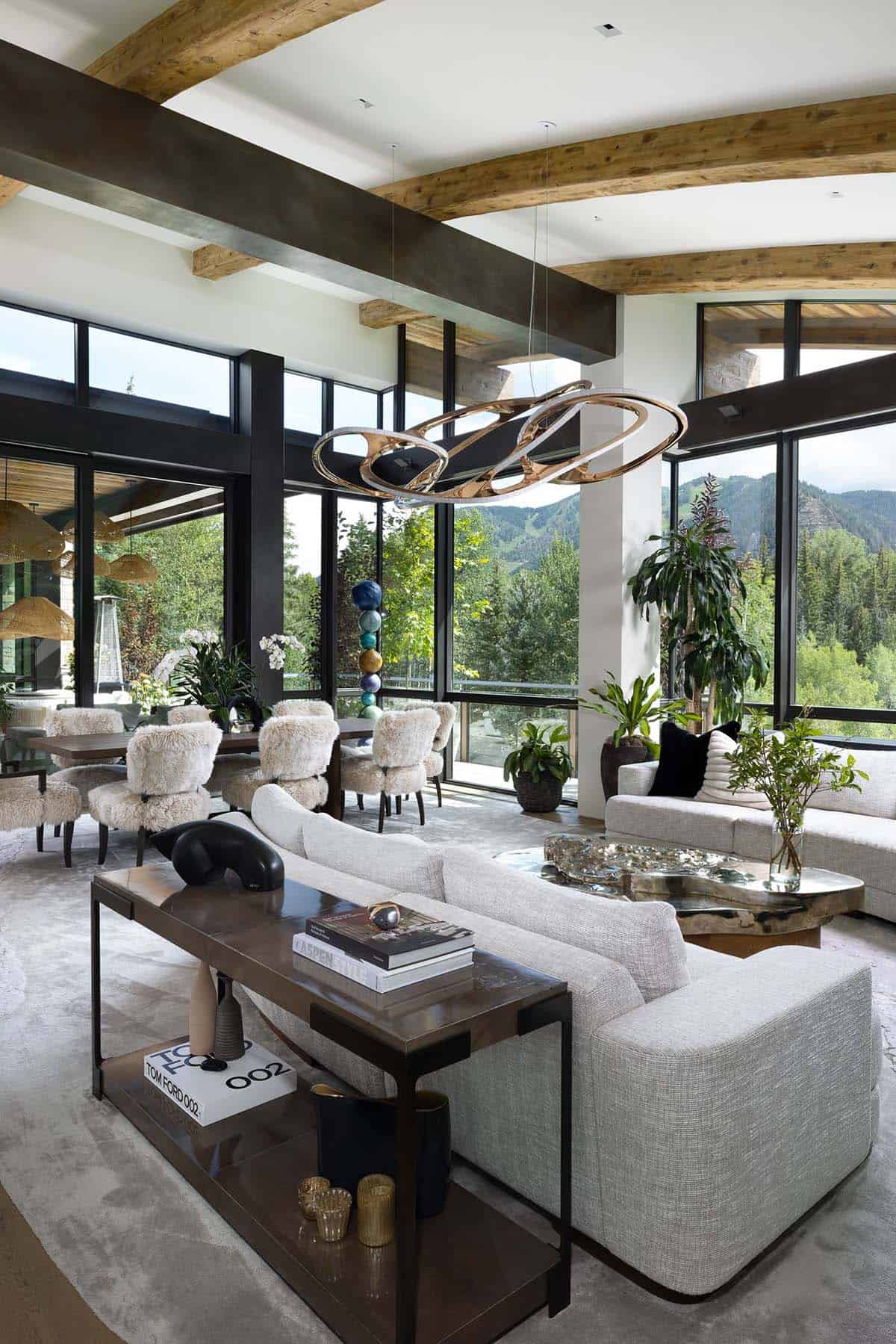 Living and dining space with a sculptural bronze chandelier, fur-covered chairs, and mountain views