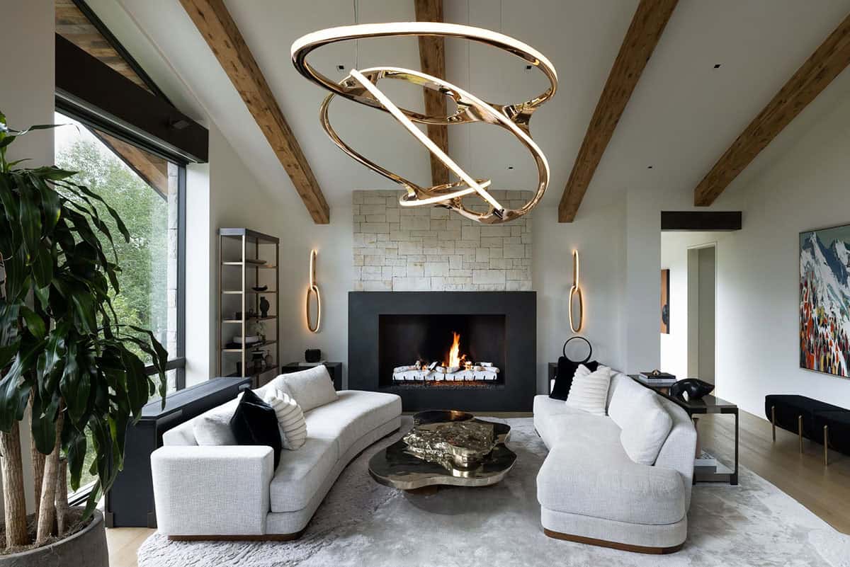Sitting room with a stone fireplace, curved white sofas, and an organic gold chandelier