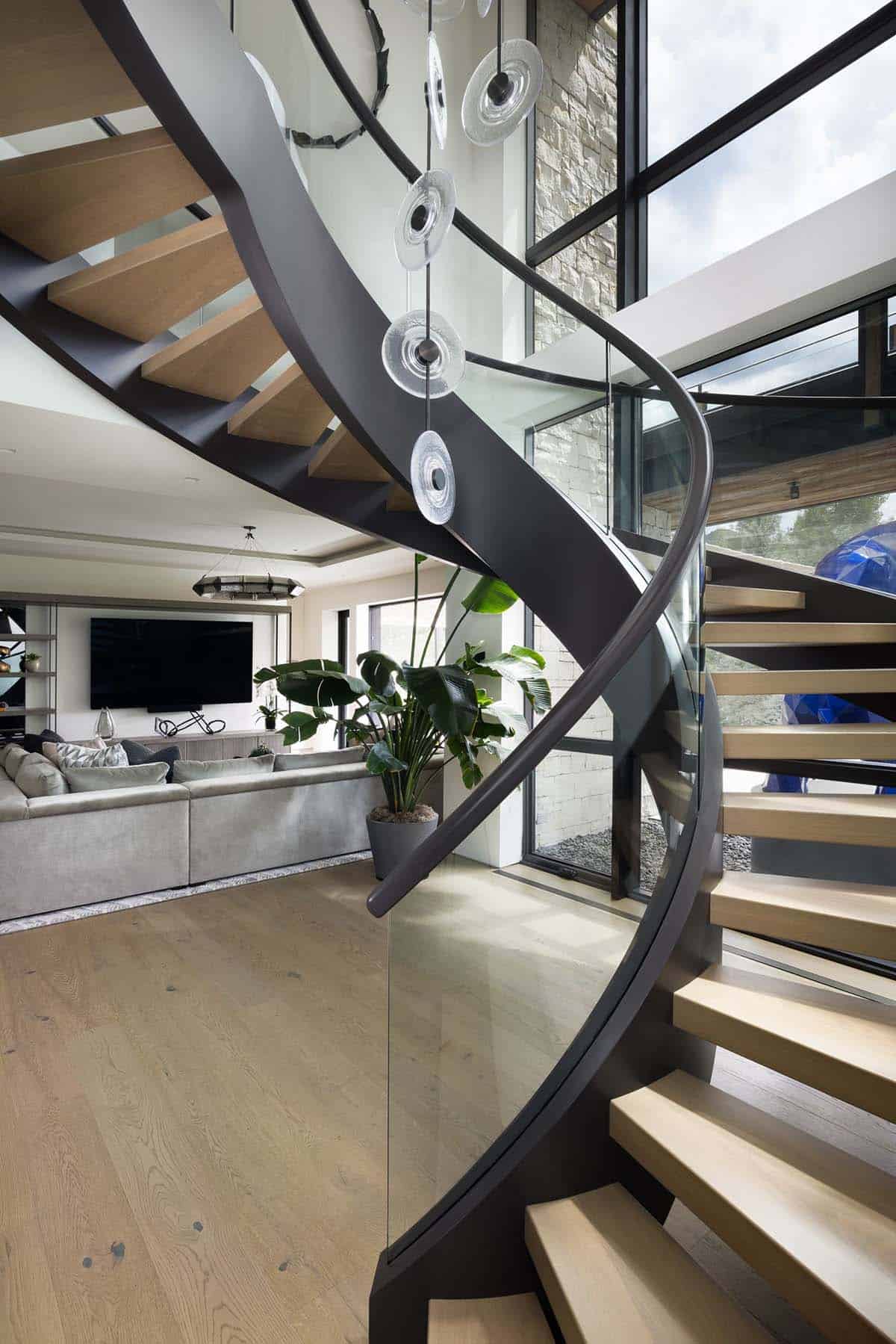 Sculptural spiral staircase with glass railing and hanging glass disc pendants