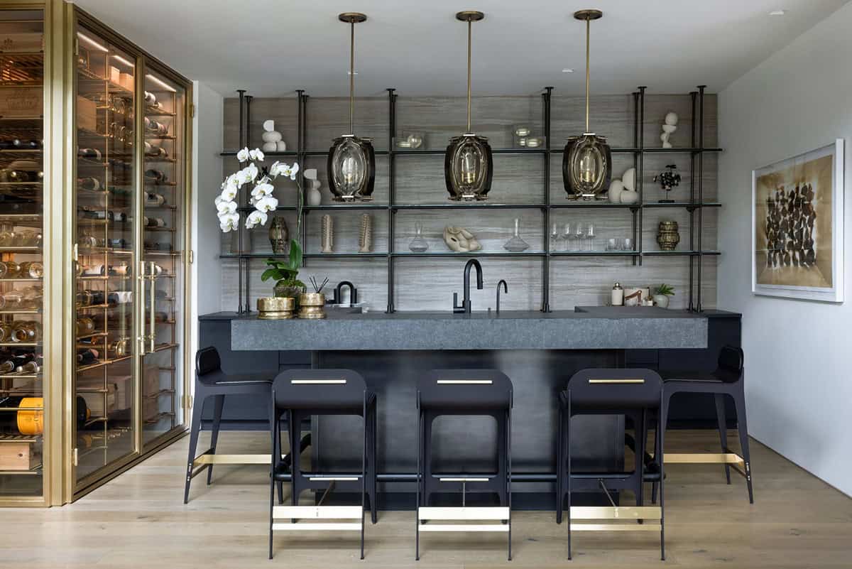 Basement bar with a stone counter, black stools, open metal shelving, and a glass wine cabinet