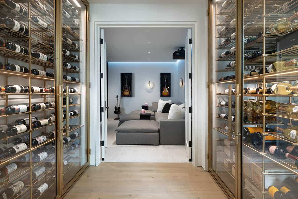 Glass-and-brass wine cabinets leading to a media room with framed guitars