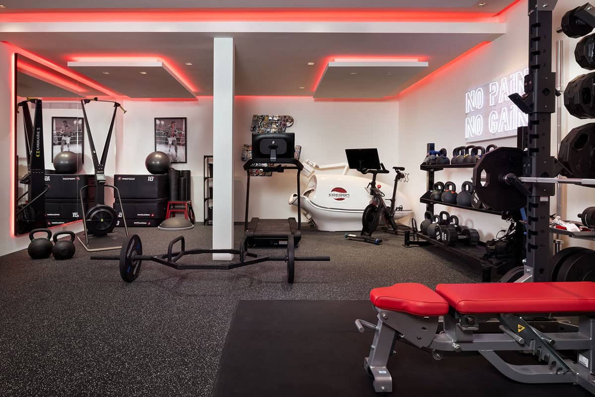 Home gym with red LED lighting, weight rack, bike, treadmill, and a "No Pain No Gain" neon sign