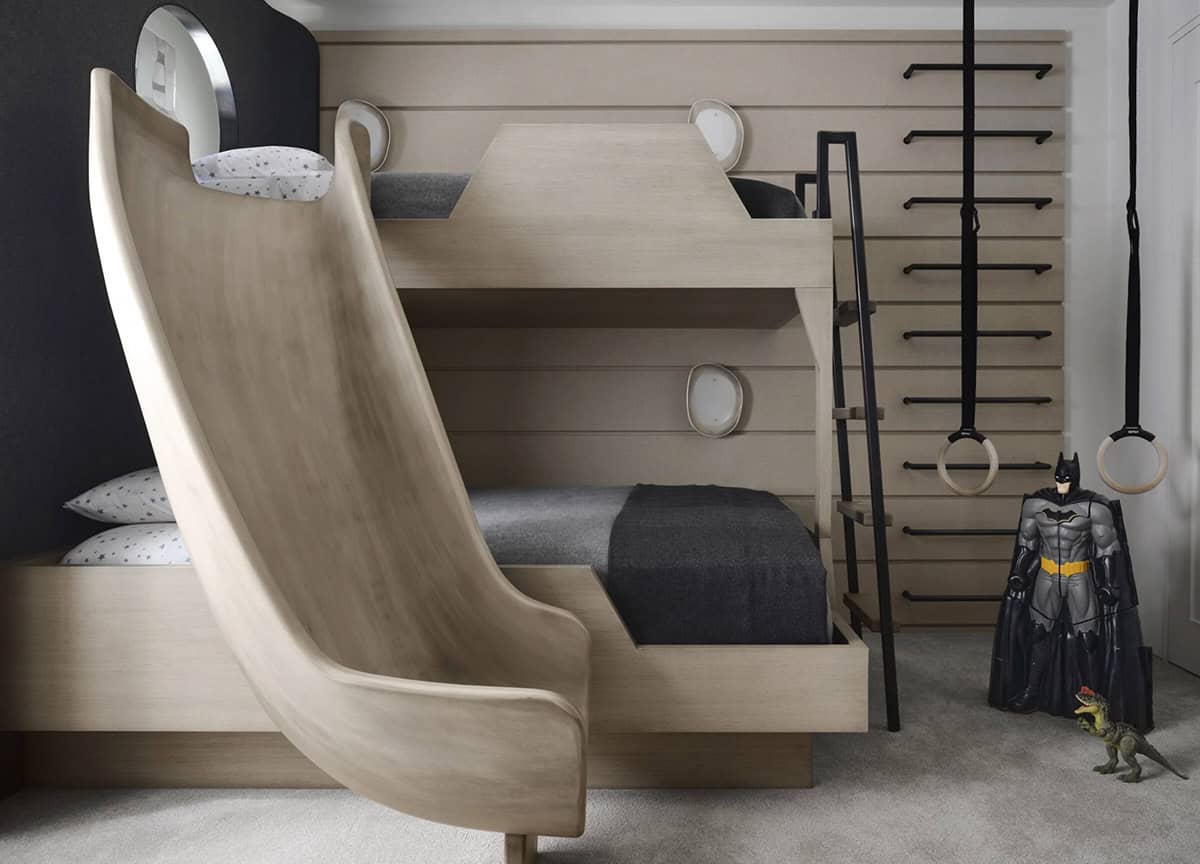 Kids' bunk room with a curved wood slide, climbing wall, gymnastic rings, and a Batman figure