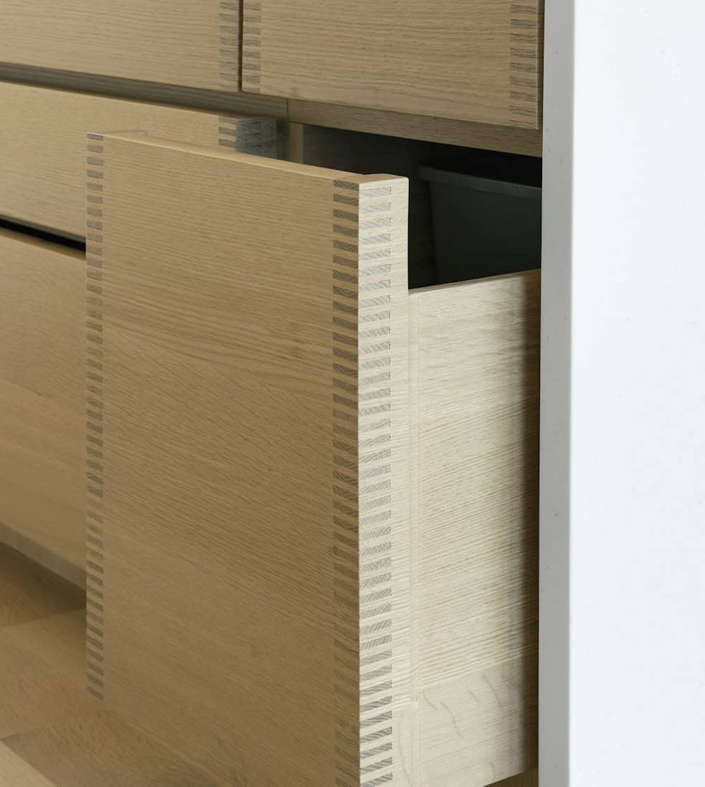 Close-up of a white oak drawer pulled open, showing finely crafted finger joint corners