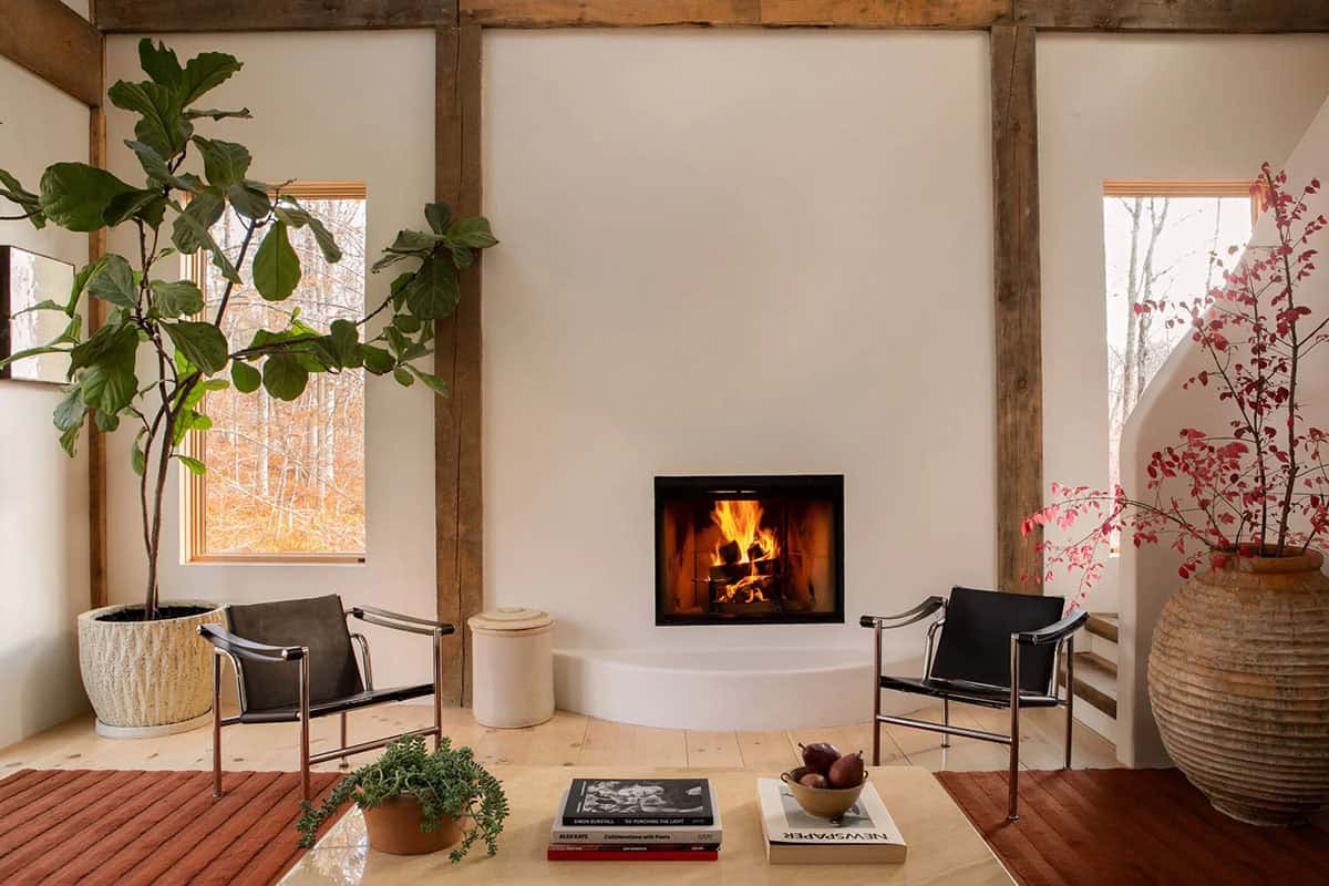 Fireplace wall with two leather and chrome chairs, a fiddle-leaf fig, and a rust-colored rug