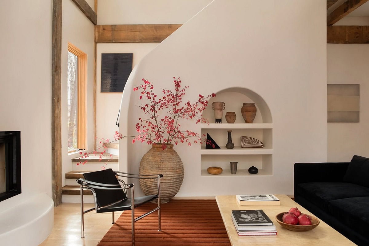 Living room with a curved plaster staircase wall, an arched shelf niche, and a velvet black sofa