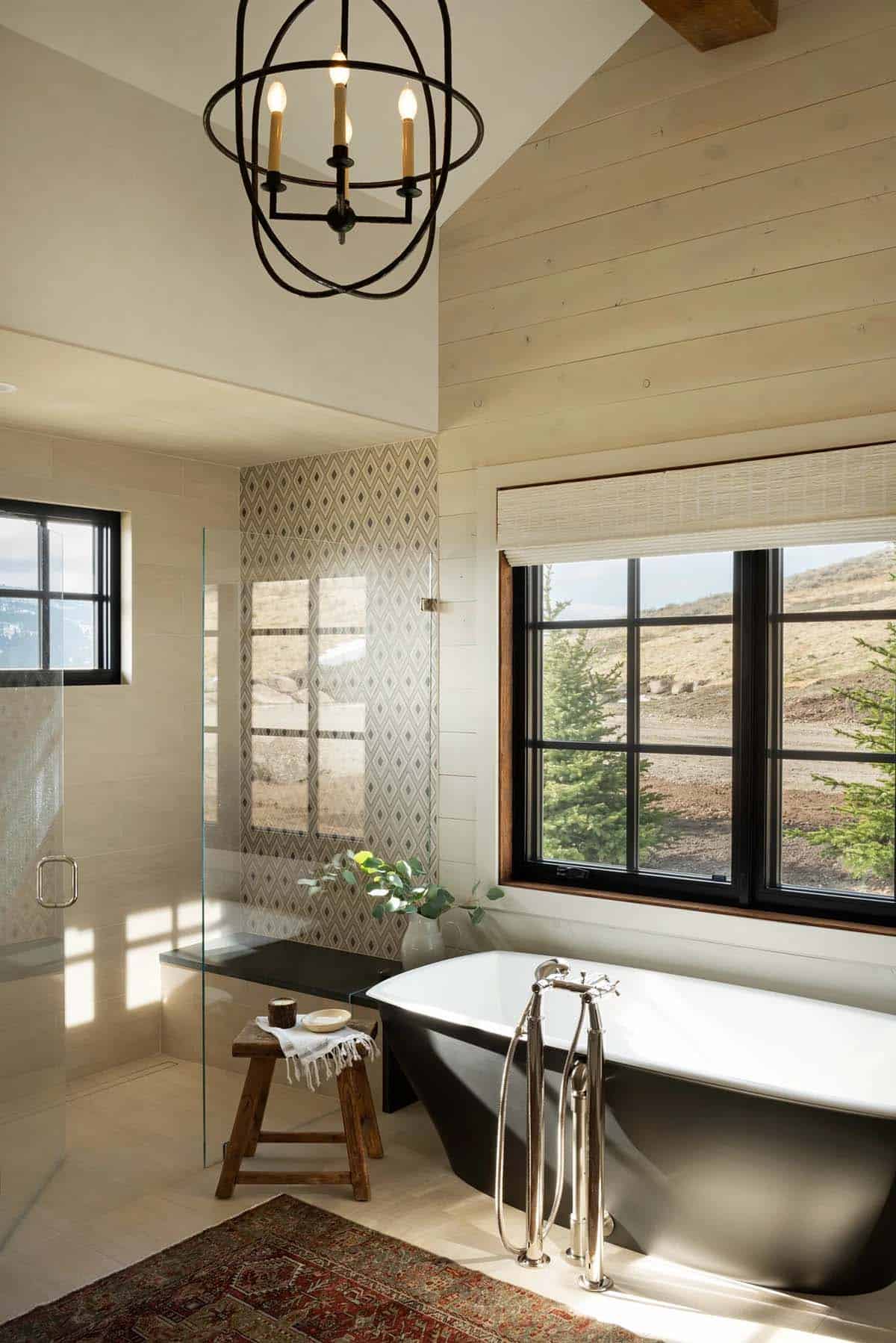 Bathroom with a black freestanding tub, polished nickel floor-mount faucet, iron orb chandelier and glass walk-in shower