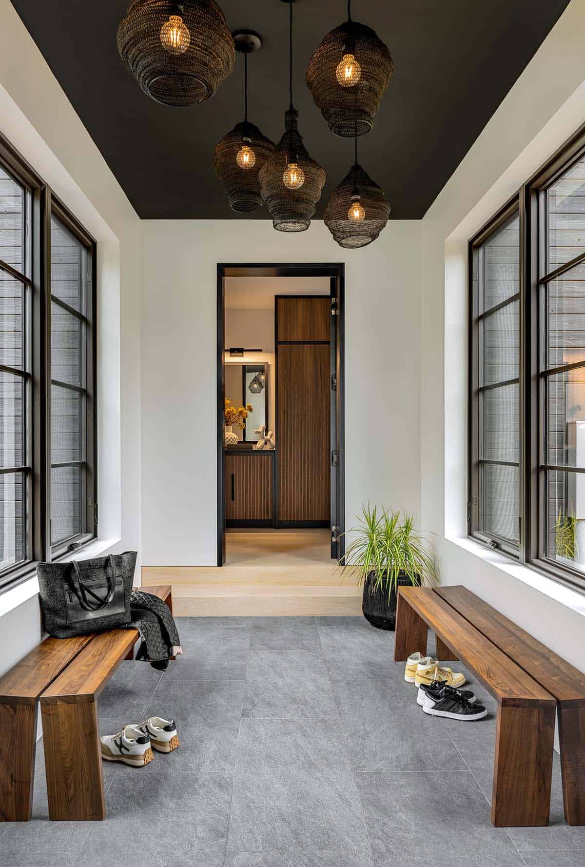 Mudroom with walnut benches, gray stone tile, a black ceiling, and a cluster of woven pendant lights