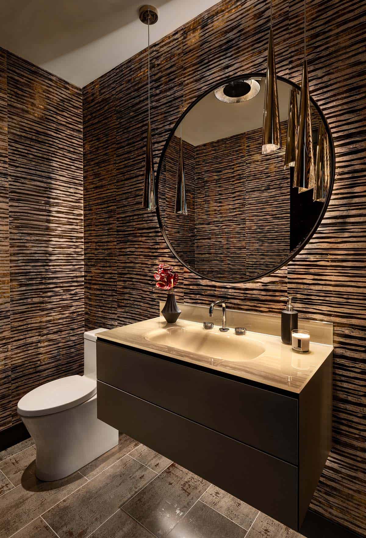 Powder room with striped metallic wallpaper, a round black mirror, cone pendants, and a floating vanity