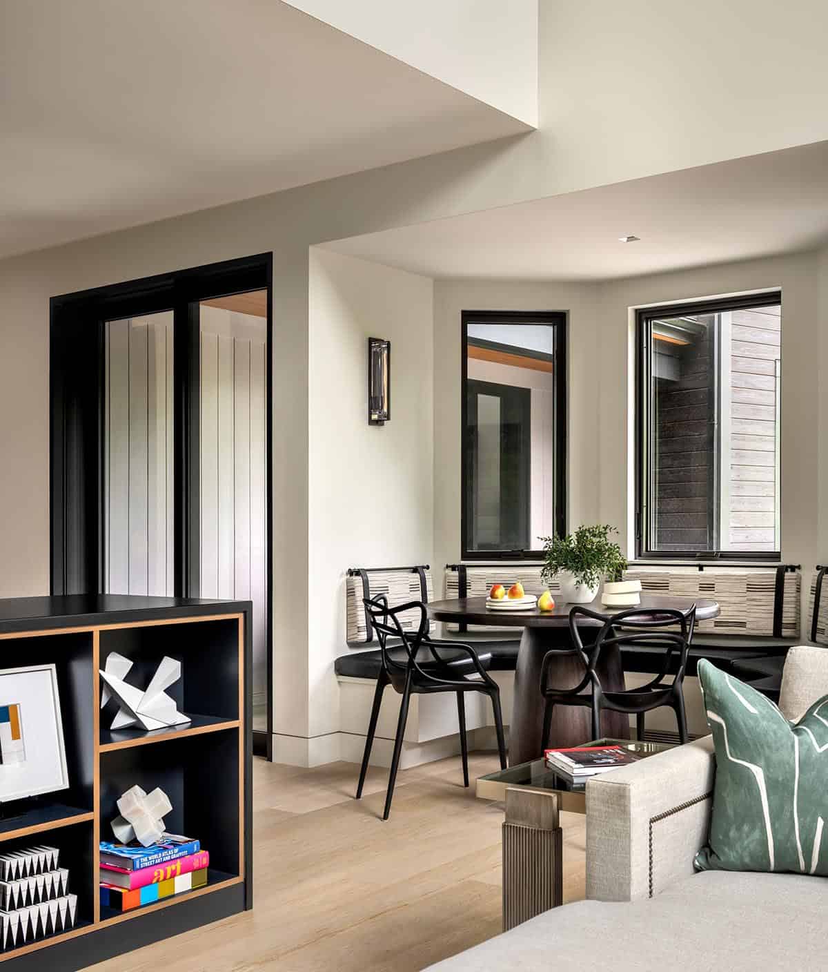 Breakfast nook with a curved banquette, round dark wood table, and black chairs, seen from the living room