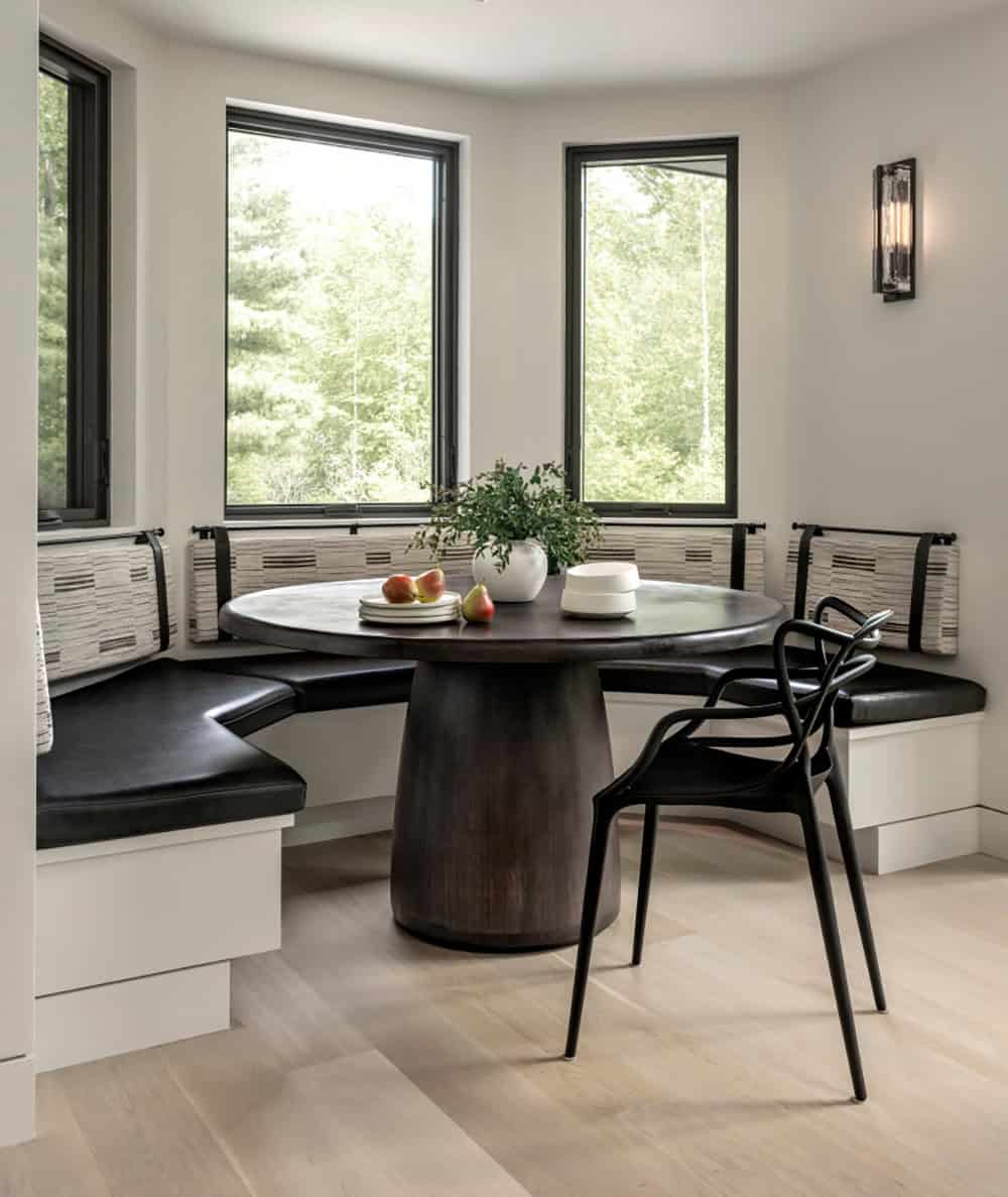 Curved banquette with black leather seats and striped back cushions around a round pedestal table