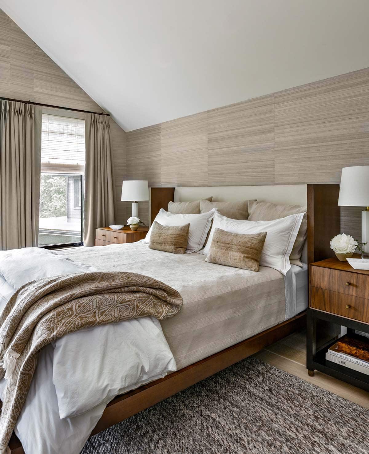 Bedroom with grasscloth walls, a vaulted ceiling, a walnut bed, and white and tan linen bedding
