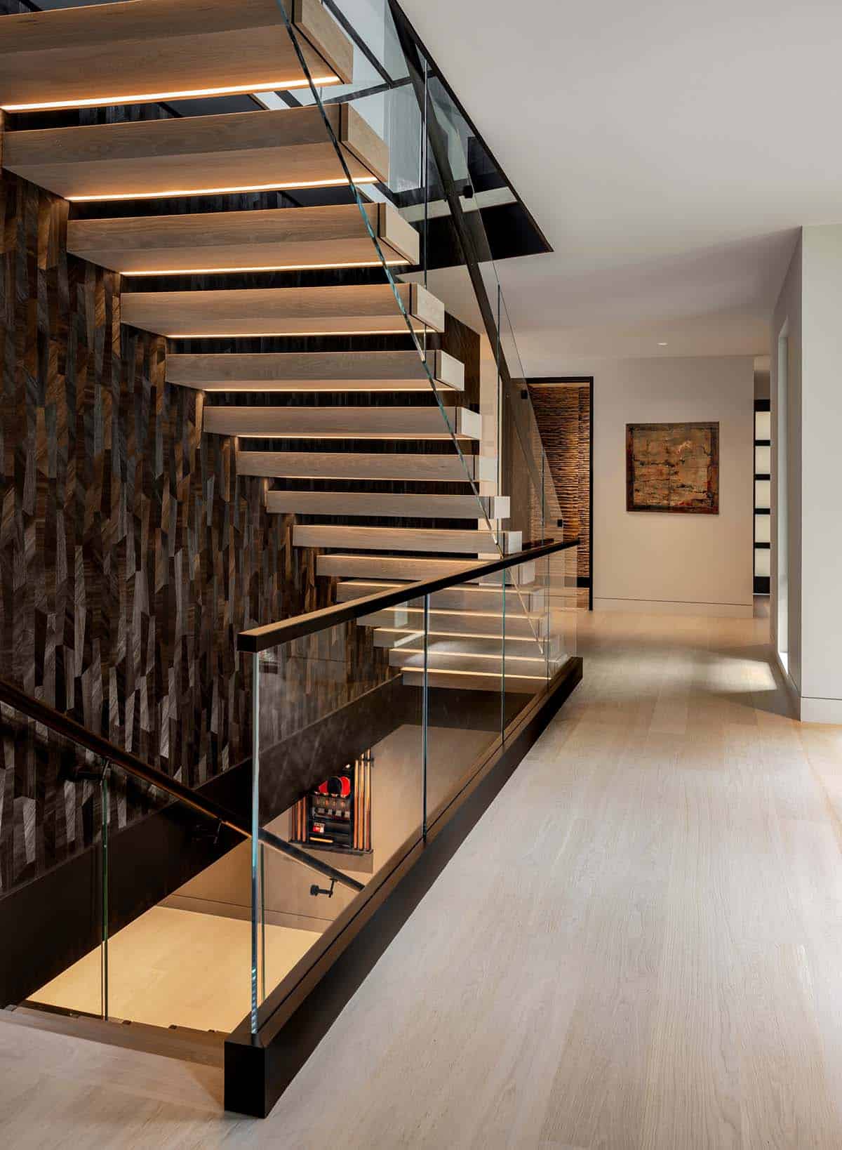 Upper landing beside the floating staircase and glass railing, with the game room visible below
