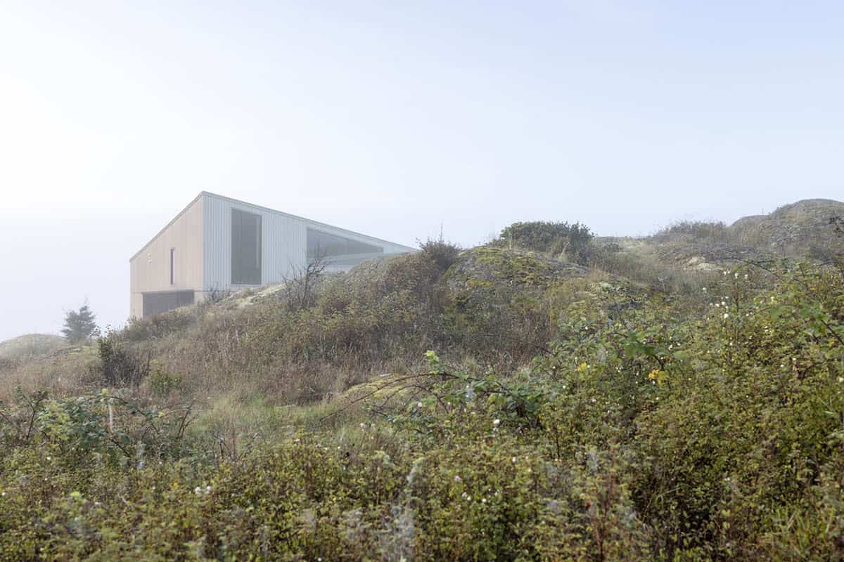 House perched among rocks and shrubs, partly veiled in fog