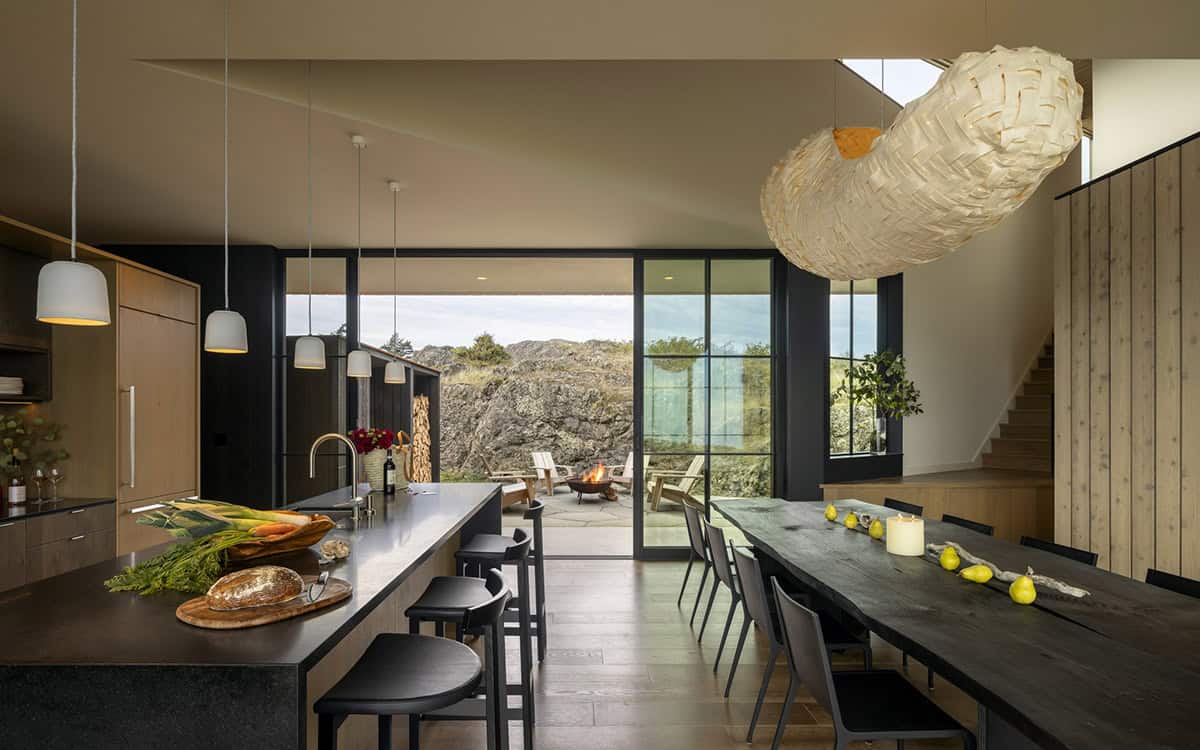 Kitchen and dining area opening to a patio with a fire pit, beneath a large woven pendant light