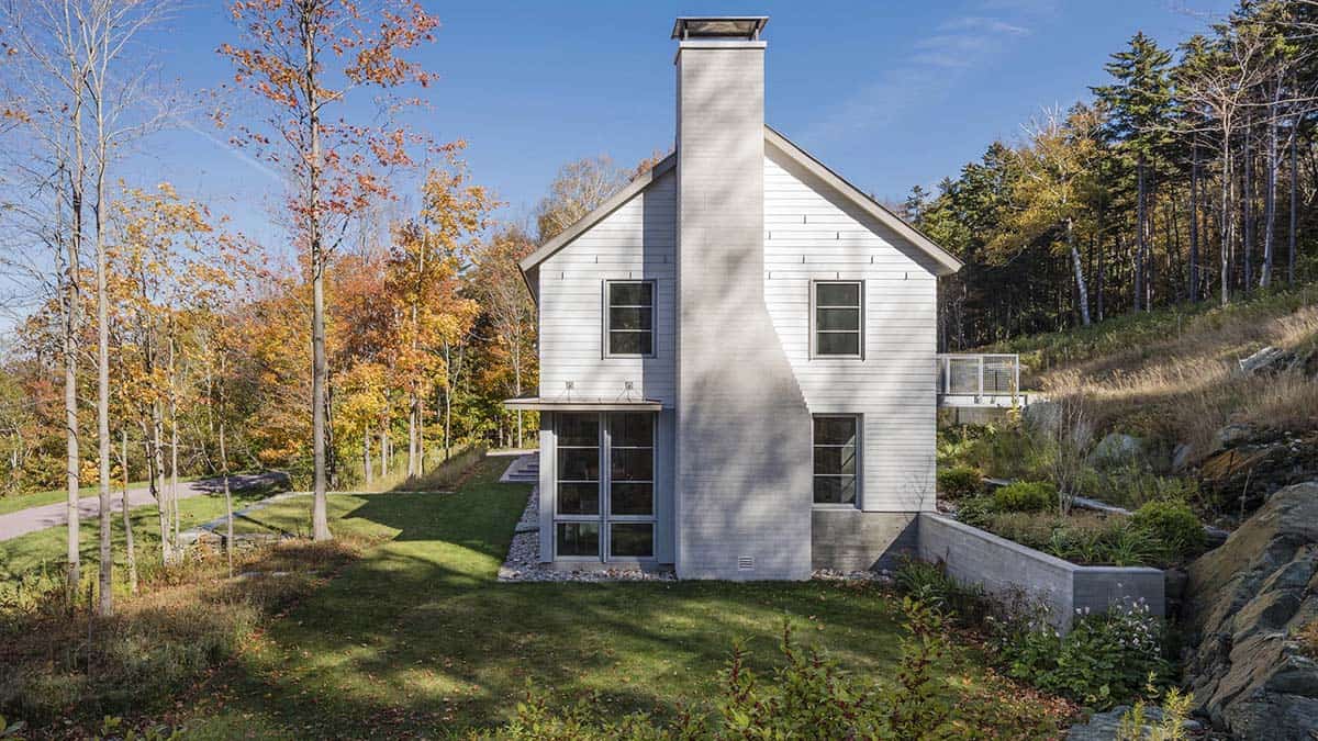 Side facade with tall brick chimney and stone retaining wall