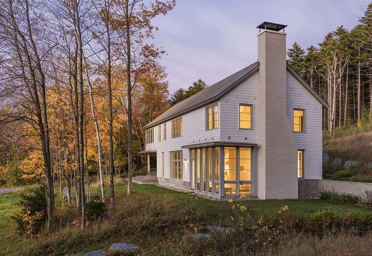 Illuminated corner windows and brick chimney on the home at dusk