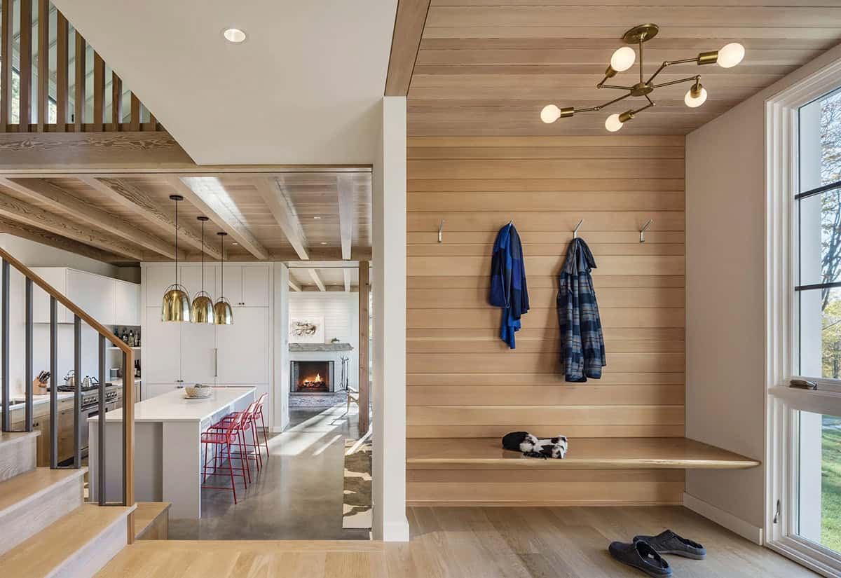 Wood-paneled entry with built-in bench, coat hooks and view to the kitchen