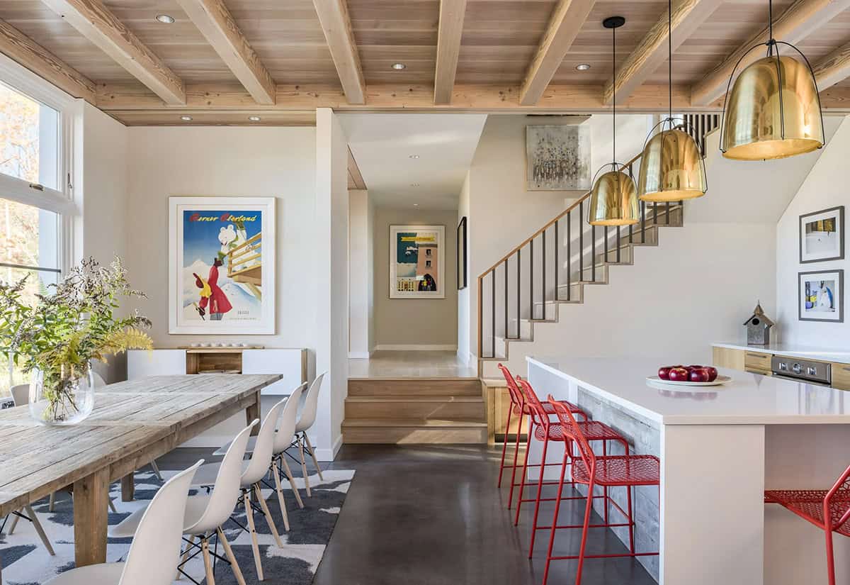 Open dining and kitchen with exposed timber beams and brass pendants