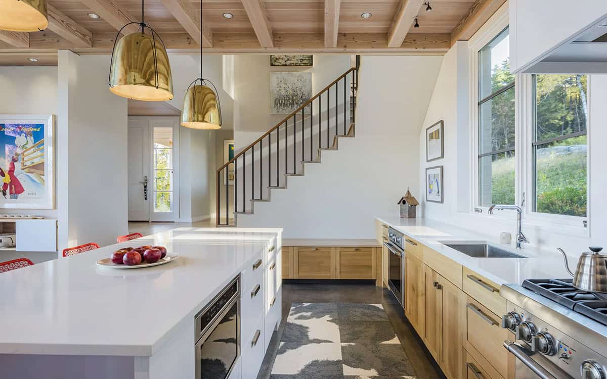 Kitchen with white island, oak cabinets and a floating stair
