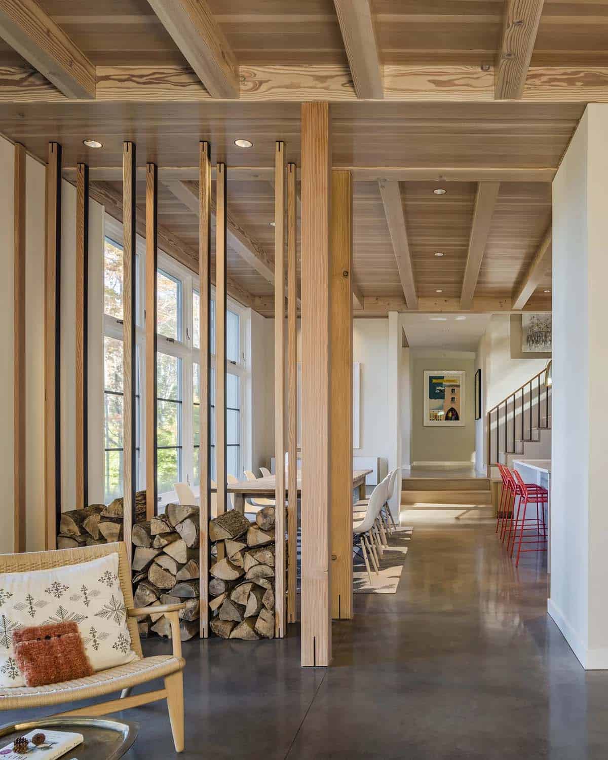 Timber slat screen with stacked firewood separating living and dining areas