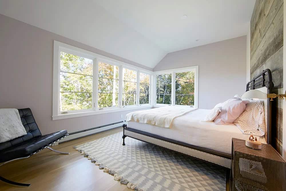 Bedroom with corner windows, reclaimed wood accent wall and iron bed