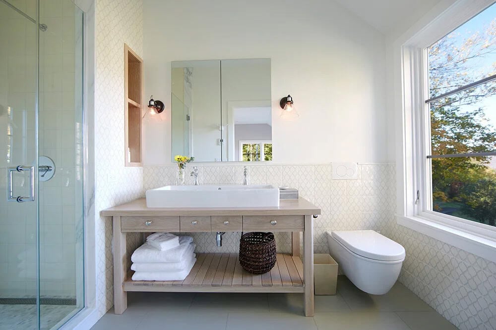 Bathroom with oak vanity, vessel sink and patterned tile beside a tall window