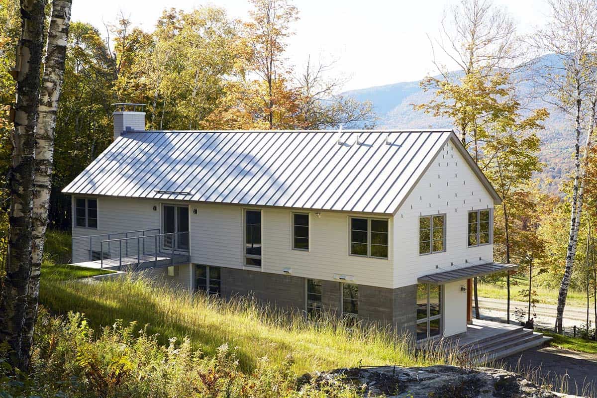 Gabled home with a metal roof, side bridge and board-formed concrete base