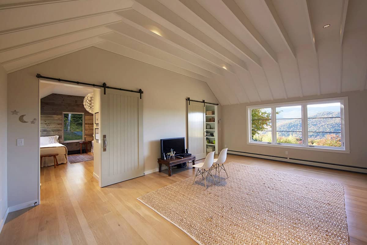 Upper-level lounge with vaulted ceiling, barn doors and mountain views