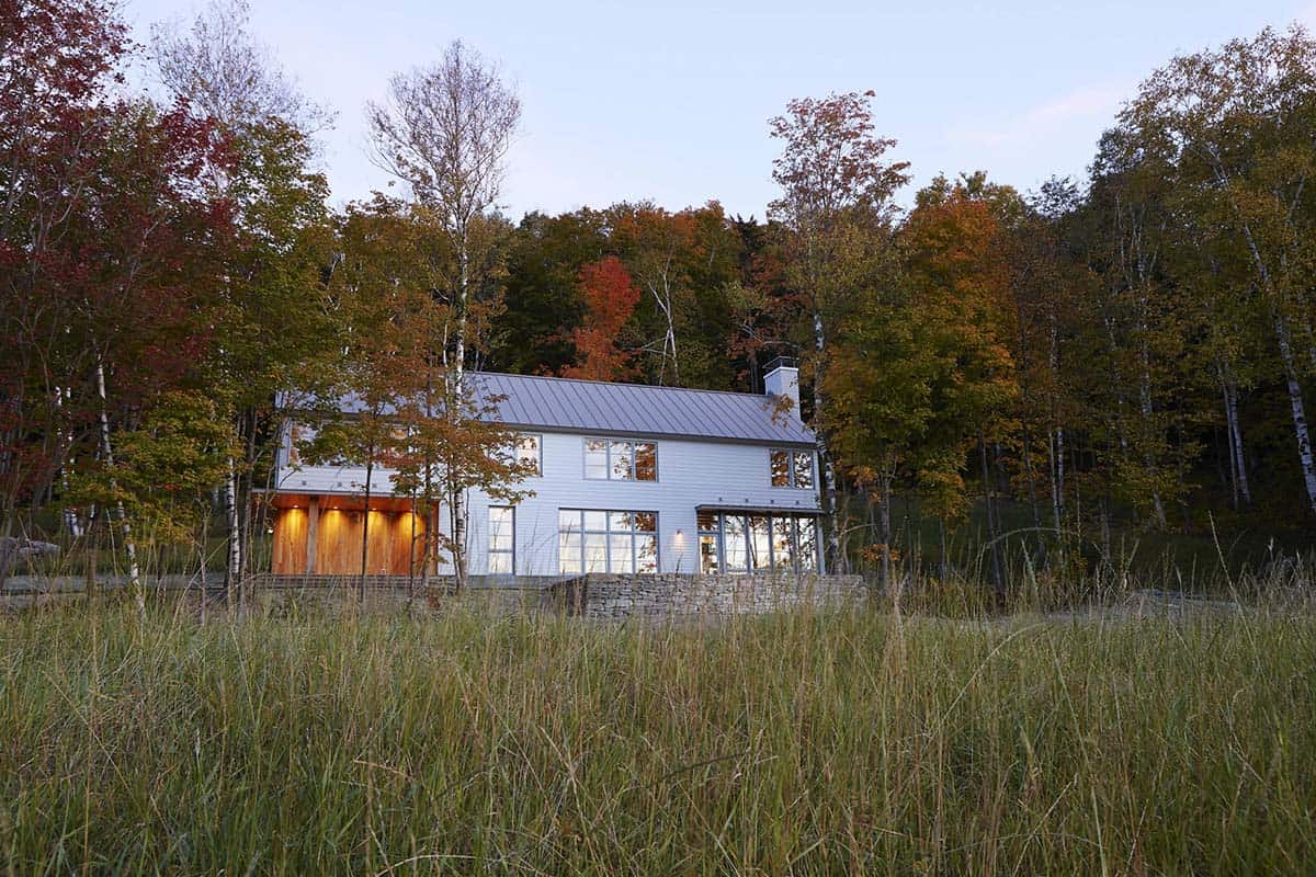 Distant view of the lit home through tall grass and autumn trees