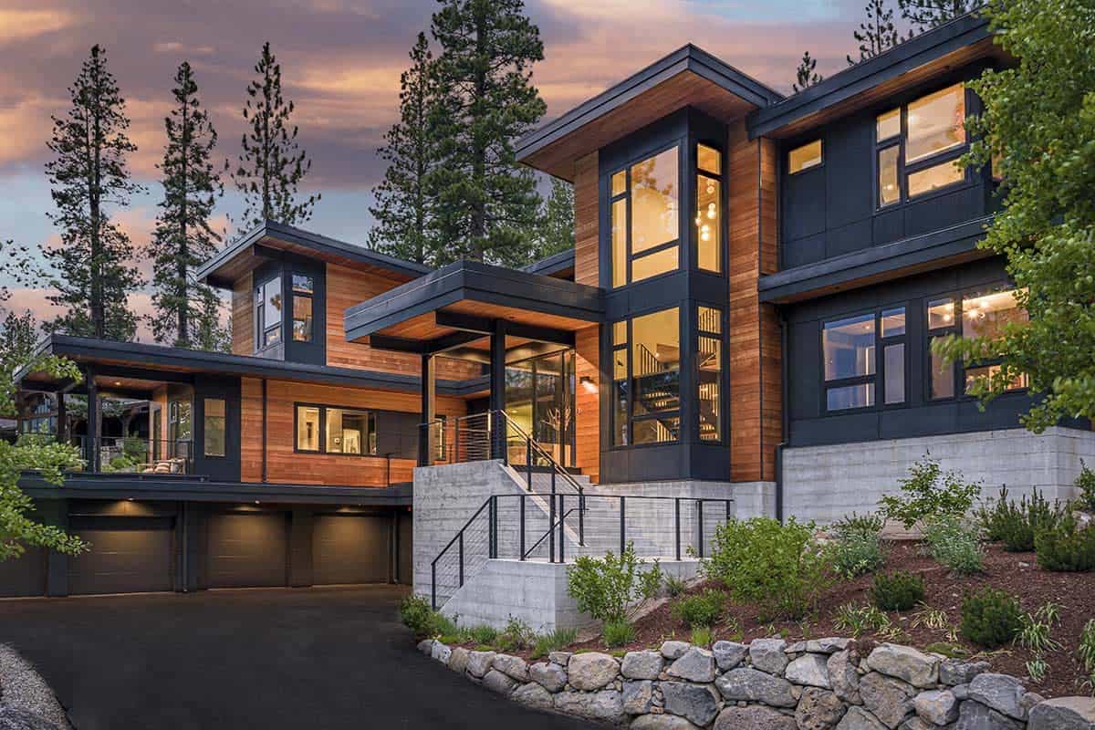 Entry front of the home with a cantilevered roof, corner glass tower, cedar siding, and cable-rail steps