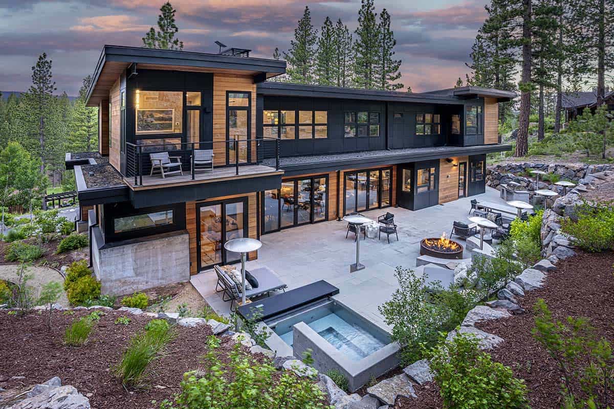 Rear patio with a fire pit, hot tub, and lounge seating below a two-story cedar and black-paneled facade