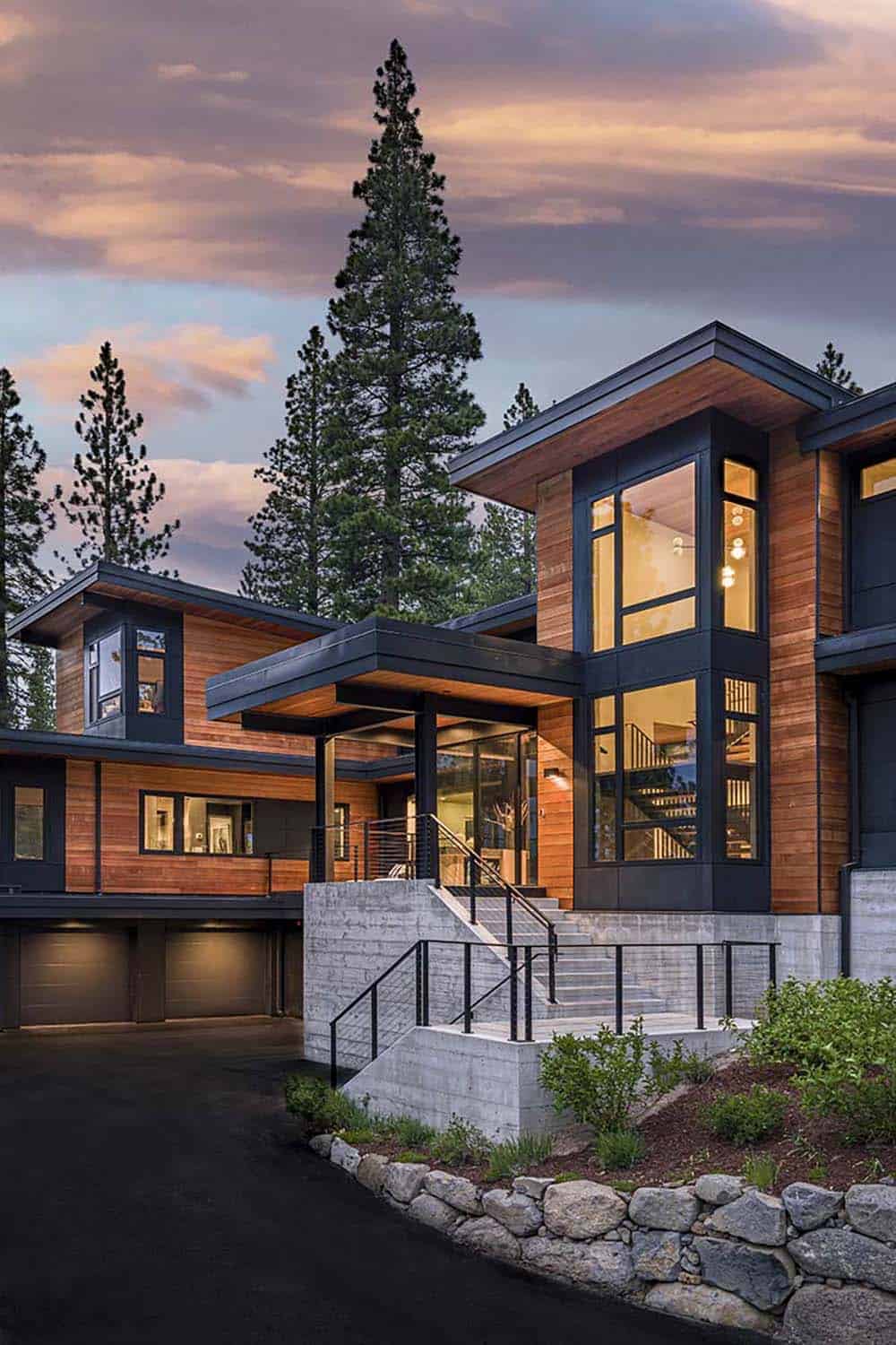 Close view of the entry with a tall glass bay window, black steel canopy, and stone retaining wall