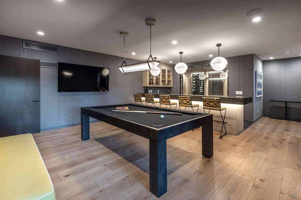 Game room with a black pool table, wet bar with leather stools, wine display, and a wall-mounted TV