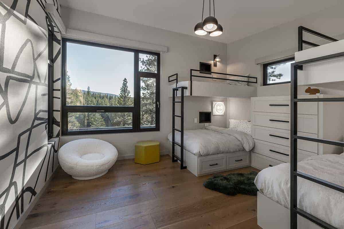 Bunk room with built-in bunks, a graphic black-and-white accent wall, a white round chair, and a mountain view