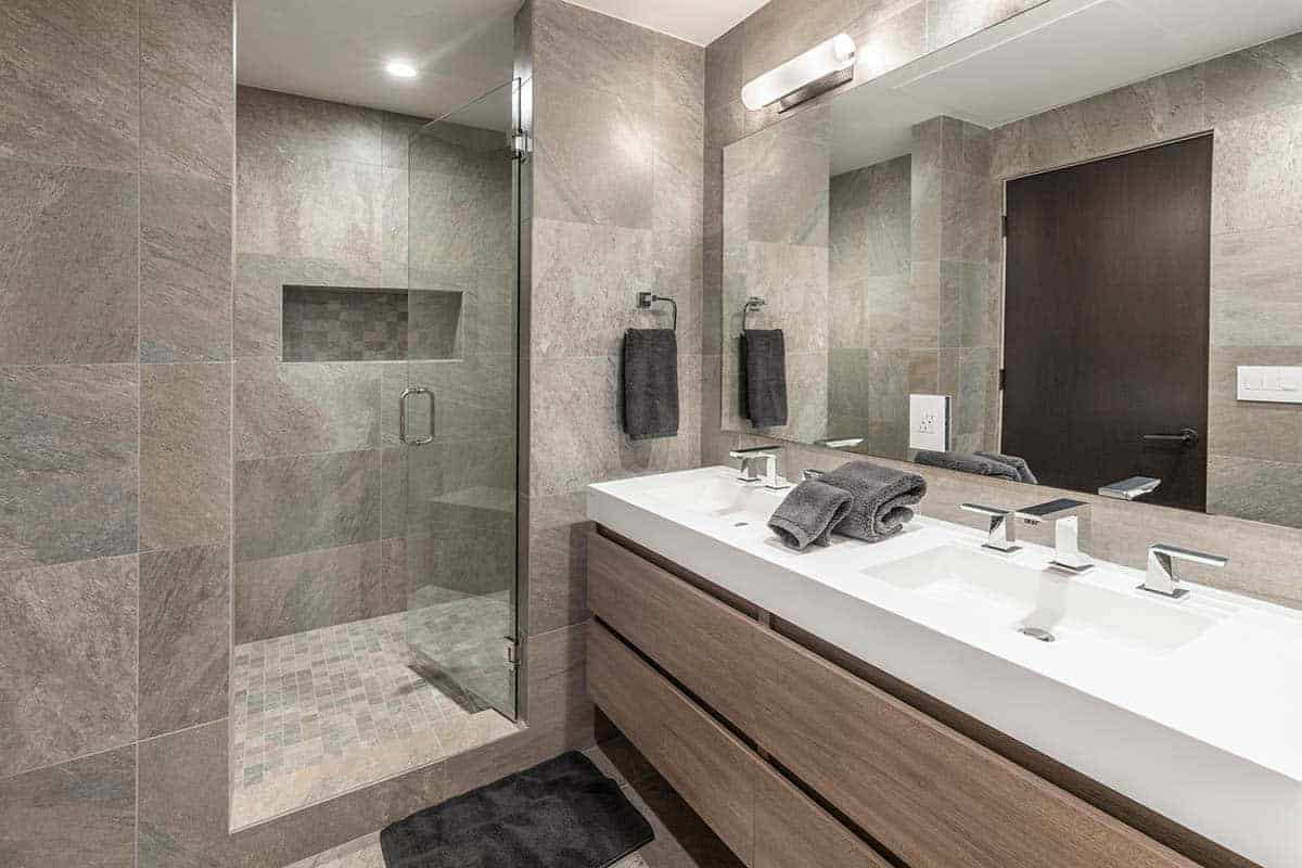 Bathroom with a gray tile shower, a white double vanity with wood drawers, and a large mirror