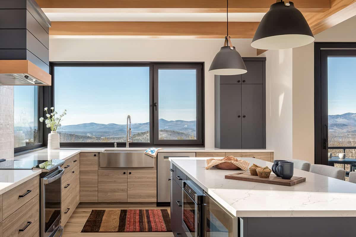 Kitchen with wood beams, black pendant lights, and a sink window facing the mountains