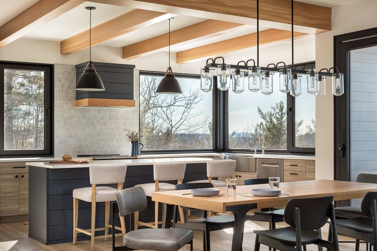 Open kitchen and dining area with wood beams, clear-glass pendants, and a long oak table