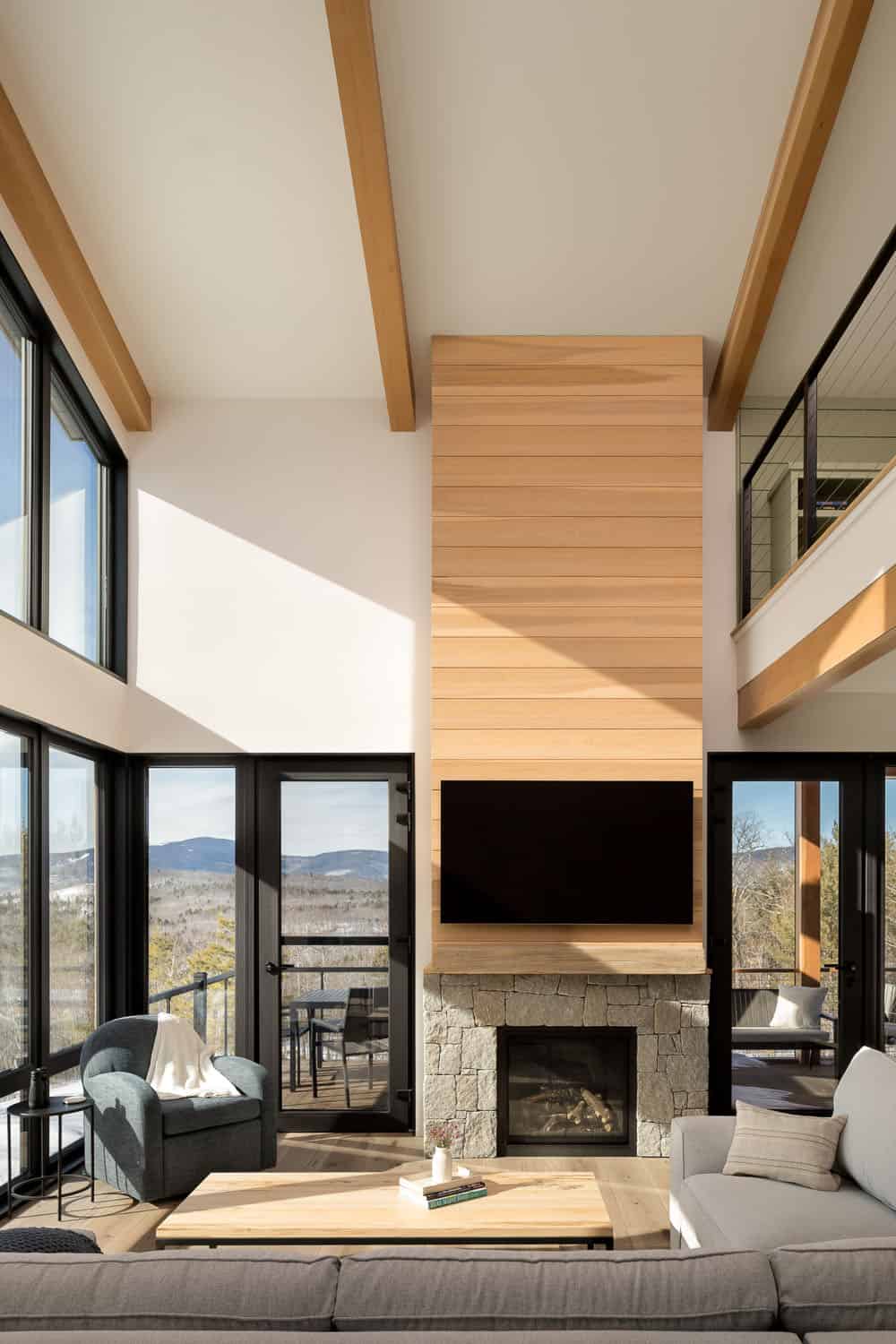 Double-height living room with a cedar-clad fireplace wall, stone hearth, and exposed beams