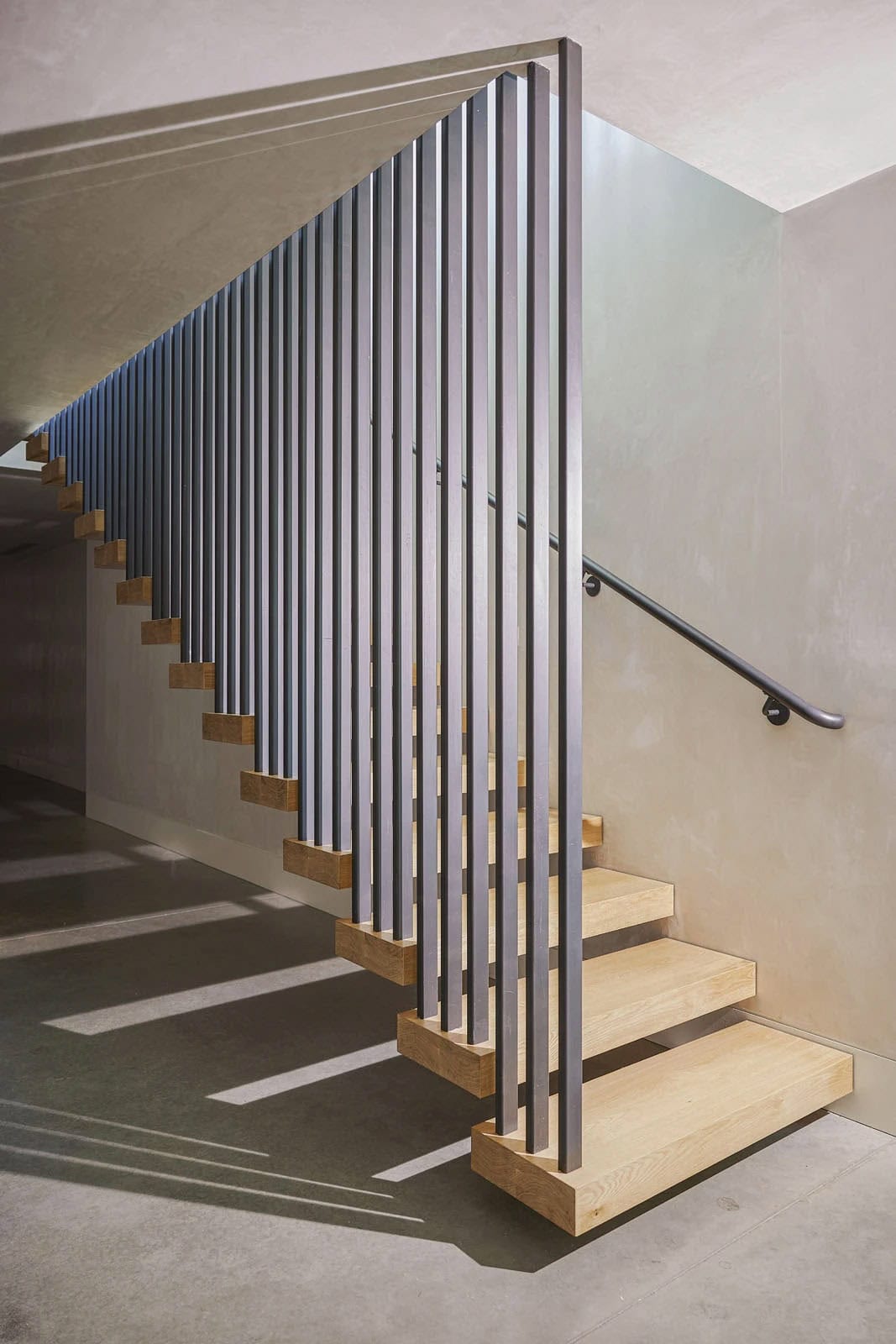 Floating white oak stairs with black steel vertical balusters
